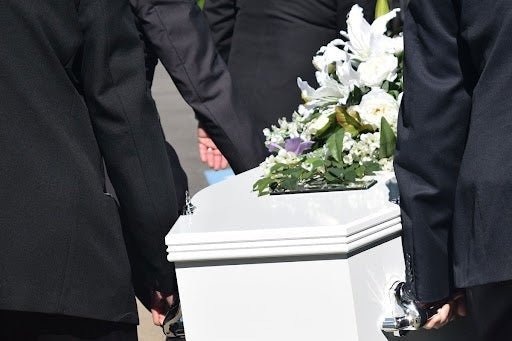 people carrying white casket with flowers