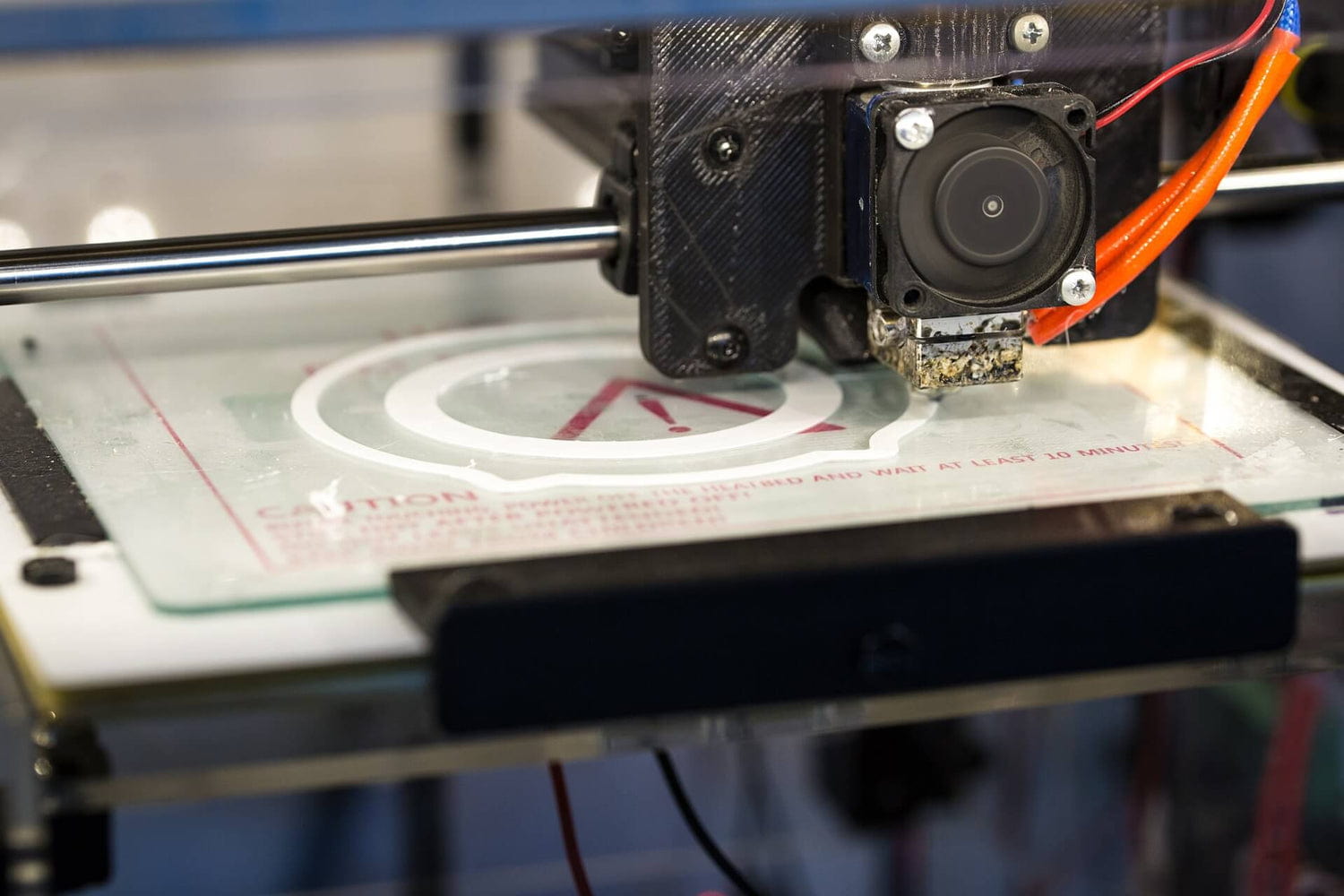 3D printer creating a white circular pattern on a glass platform