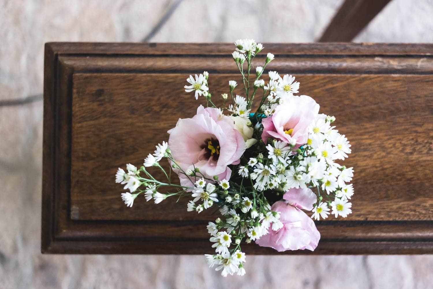 pink and white flowers on top of wooden casket