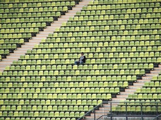 one person sitting in a green stadium seat alone